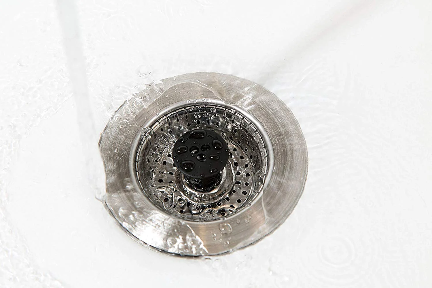 A kitchen strainer basket holding scraps back at the drain opening, where they can go in the trash instead of the pipe.
