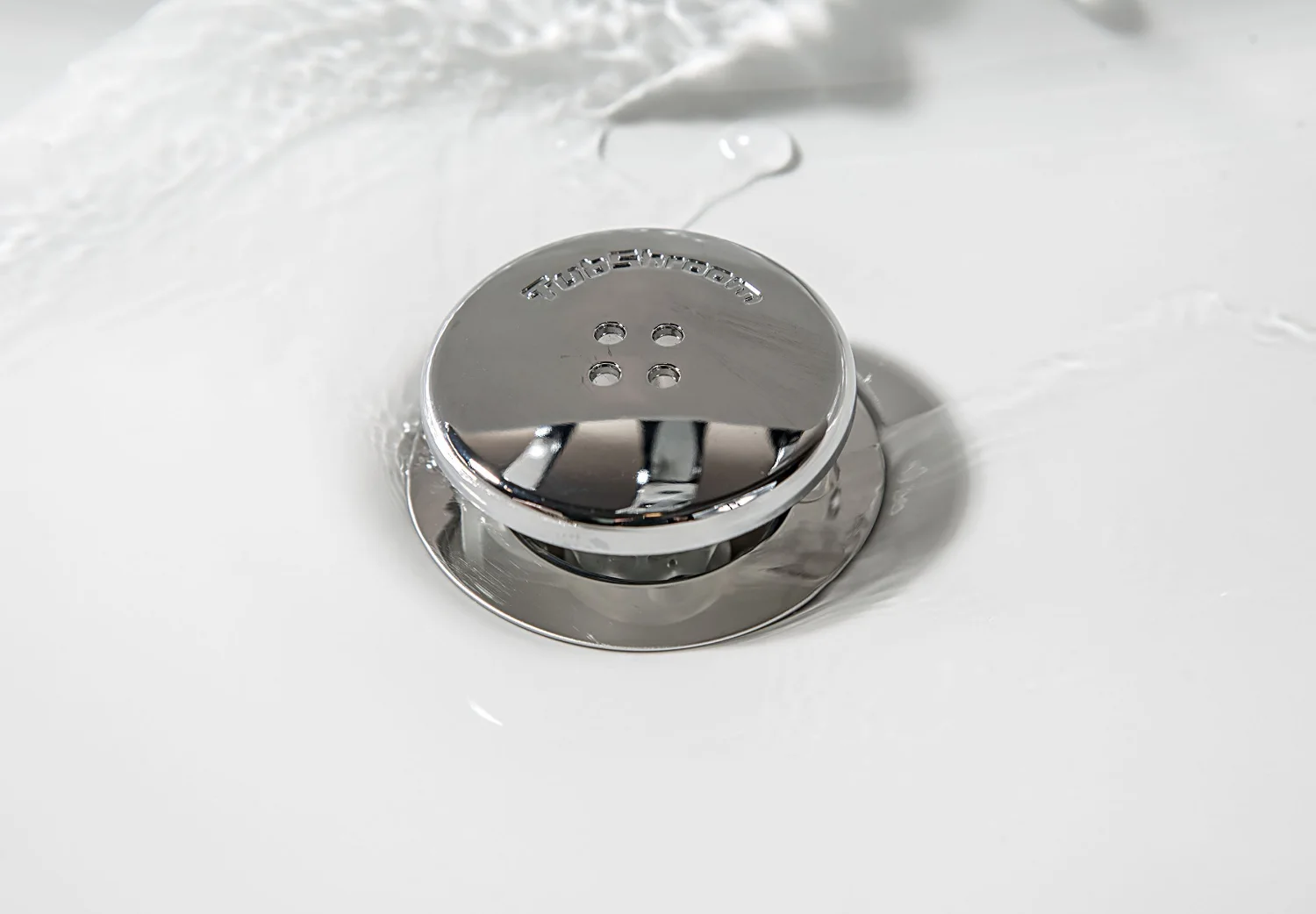 A chrome-capped catcher sitting in a tub drain where the stopper used to be.